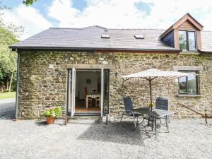 a stone cottage with a table and an umbrella at Tawelfan in Beulah