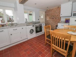 a kitchen with white cabinets and a wooden table at 27 Borthyn in Ruthin