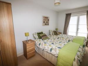 Un dormitorio con una cama y una mesa con una lámpara. en 24 Rhodewood House, en Saundersfoot