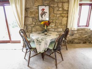a dining room table with chairs and a stone wall at Brunnion Cottage in Hayle