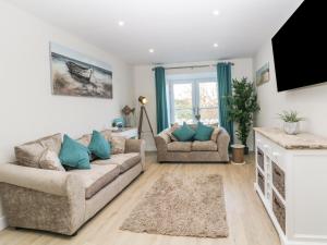 a living room with two couches and a tv at 6 Bay View in Benllech