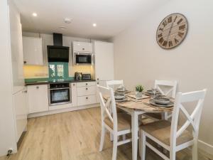a kitchen with a table and chairs and a clock on the wall at 6 Bay View in Benllech