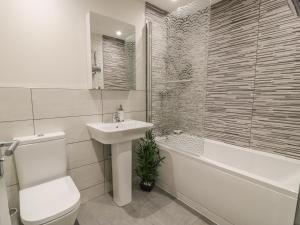 a bathroom with a sink and a toilet and a bath tub at 6 Bay View in Benllech +5 photos