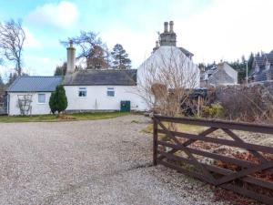 a wooden fence in front of a white house at Riemore in Tomintoul