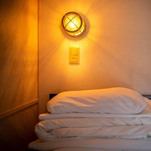 a room with a bed with a light on the wall at Super Hotel Nagaizumi Numazu Inter in Nagaizumi