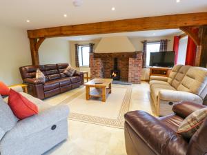 a living room with leather furniture and a fireplace at Tyn Y Celyn Isaf in Clocaenog