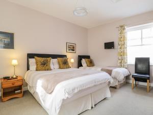 a bedroom with two beds and a chair at Swinside Cottage in Keswick