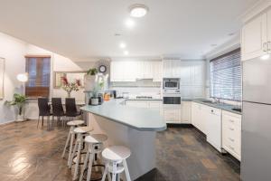 a kitchen with white cabinets and bar stools at Boutique Private Rm situated in the heart of Burwood 7 - ROOM ONLY in Sydney