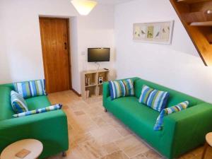 uma sala de estar com um sofá verde e uma televisão em The Old Cottage em Weston-super-Mare
