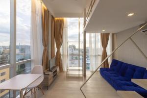 a living room with a blue couch and large windows at Selah Pods Hotel Manila in Manila