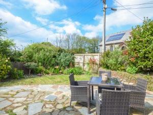 a patio with a table and chairs in a yard at Bee Hive Cottage in Morwenstow