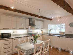 a kitchen with white cabinets and a table with chairs at Pottery Barn in Branscombe