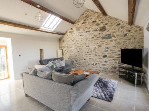 a living room with a stone wall and a couch at Wern Olau Cottage in Caernarfon