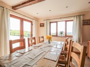 a dining room with a long table with chairs and windows at Blaen Henllan in Aberedw