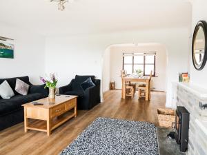 ein Wohnzimmer mit einer schwarzen Couch und einem Tisch in der Unterkunft Seal Cottage in Woolacombe