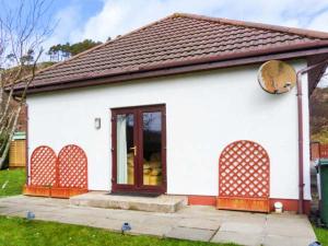 una pequeña casa blanca con techo marrón en Cooinda Cottage en Morar