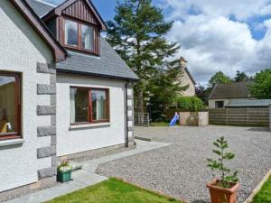 a house with a gravel driveway in a yard at Bruach Gorm Cottage in Grantown on Spey