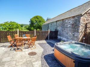 a patio with a table and chairs and a hot tub at Ysgubor - Barn in Llanddulas