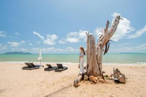 SEAnery Beach Resort في سابان بانغ: امرأة تقف بجوار شجرة على الشاطئ
