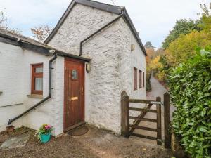 a white building with a wooden door and a fence at Happy Cow in Coleford