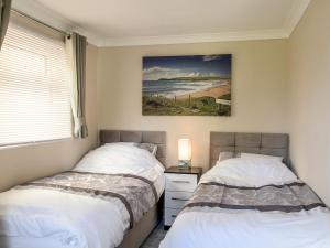two beds in a bedroom with a painting on the wall at Little Retreat in Liskeard