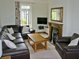 ein Wohnzimmer mit einer Ledercouch und einem Tisch in der Unterkunft Railway Cottage in Fairbourne