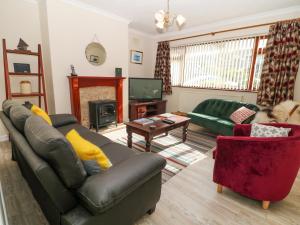 a living room with a leather couch and a tv at Eryl in Pwllheli