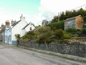 uma rua vazia com casas e uma parede de pedra em Nathaniel's Cottage em Kirkcudbright