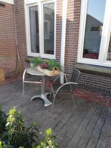 a table and chairs on a patio with two windows at B&B Het Oude Postkantoor in Yerseke