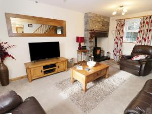 a living room with a flat screen tv and leather furniture at 60 Hyfrydle Road in Caernarfon