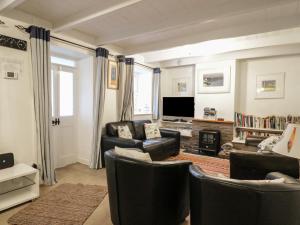 a living room with two leather chairs and a television at Daisy Cottage in Perranporth