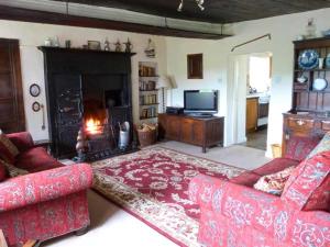 a living room with two red couches and a fireplace at High Sprintgill Cottage in Ravenstonedale