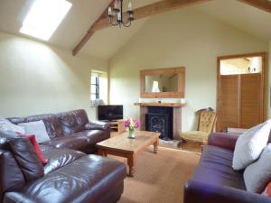 a living room with leather furniture and a fireplace at Meadow Cottage in Fowey