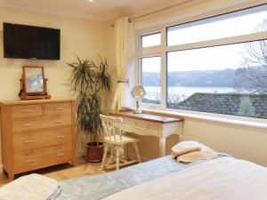 a bedroom with a bed and a desk and a window at Treetops in Fowey