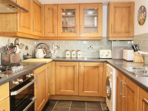 a kitchen with wooden cabinets and stainless steel appliances at Llwyn Onn in Dolwyddelan