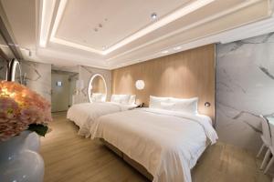 - 2 lits dans une chambre d'hôtel avec des draps blancs dans l'établissement Uya Motel, à Xinwu