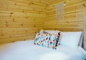a bedroom with wooden walls and a bed with pillows at Marlborough Wine Barrel Cabins in Blenheim