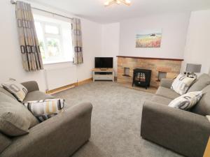 sala de estar con 2 sofás y chimenea en Ysgubor Fawr, en Caernarfon
