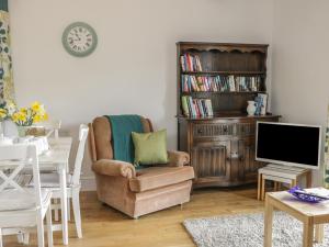 a living room with a chair and a table with a tv at Acorn Cottage 2 in Petton