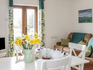 a living room with a white table and yellow flowers at Acorn Cottage 2 in Petton