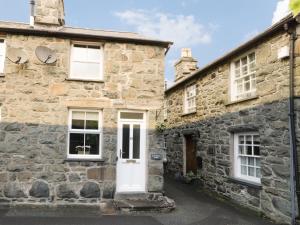 an old stone house with a white door at Cae Tanws Bach in Dolgellau