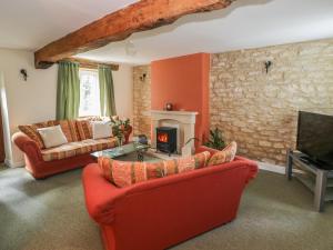 a living room with red furniture and a fireplace at 1 Westcroft Cottage in Stonehouse