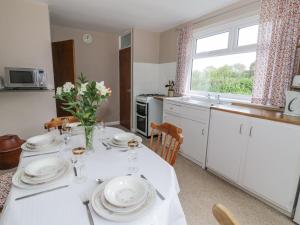 a kitchen with a table with plates and flowers on it at 1 Westcroft Cottage in Stonehouse