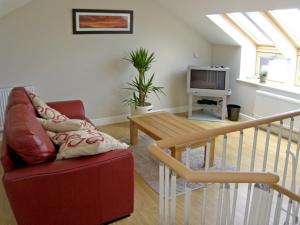 een woonkamer met een rode bank en een tafel bij Ysgubor Penrallt in Y Felinheli