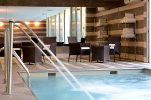 una piscina en un hotel con sillas y mesas en Holiday Inn Santiago - Airport Terminal, an IHG Hotel, en Santiago