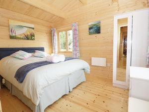 a bedroom with a bed in a log cabin at The Shippen in West Chinnock