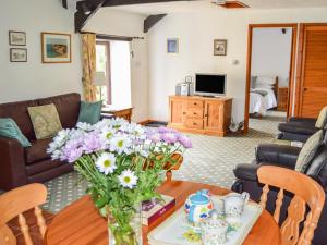 a living room with a table with flowers on it at Windbury Cottage in Hartland
