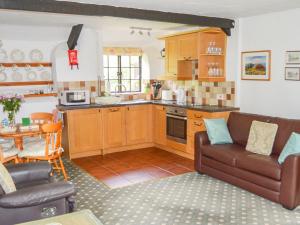a living room with a couch and a kitchen at Windbury Cottage in Hartland