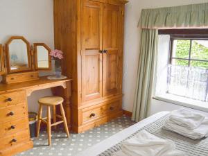 a bedroom with a wooden dresser and a mirror at Windbury Cottage in Hartland