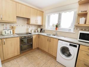 a kitchen with wooden cabinets and a washer and dryer at MACS Place in Largs